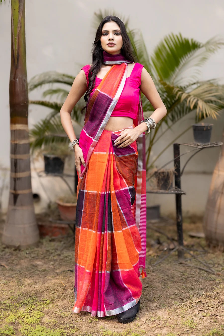 Model wearing a multicolor linen checks saree in pink, orange, and purple, lightweight and suitable for casual, office, and festive wear.