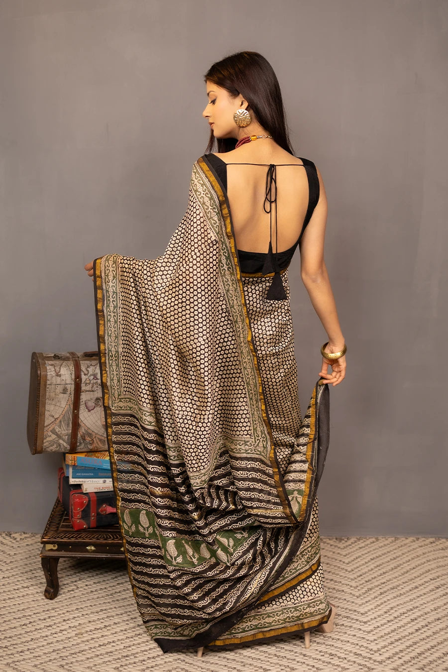 Woman wearing a patterned saree with a grey background