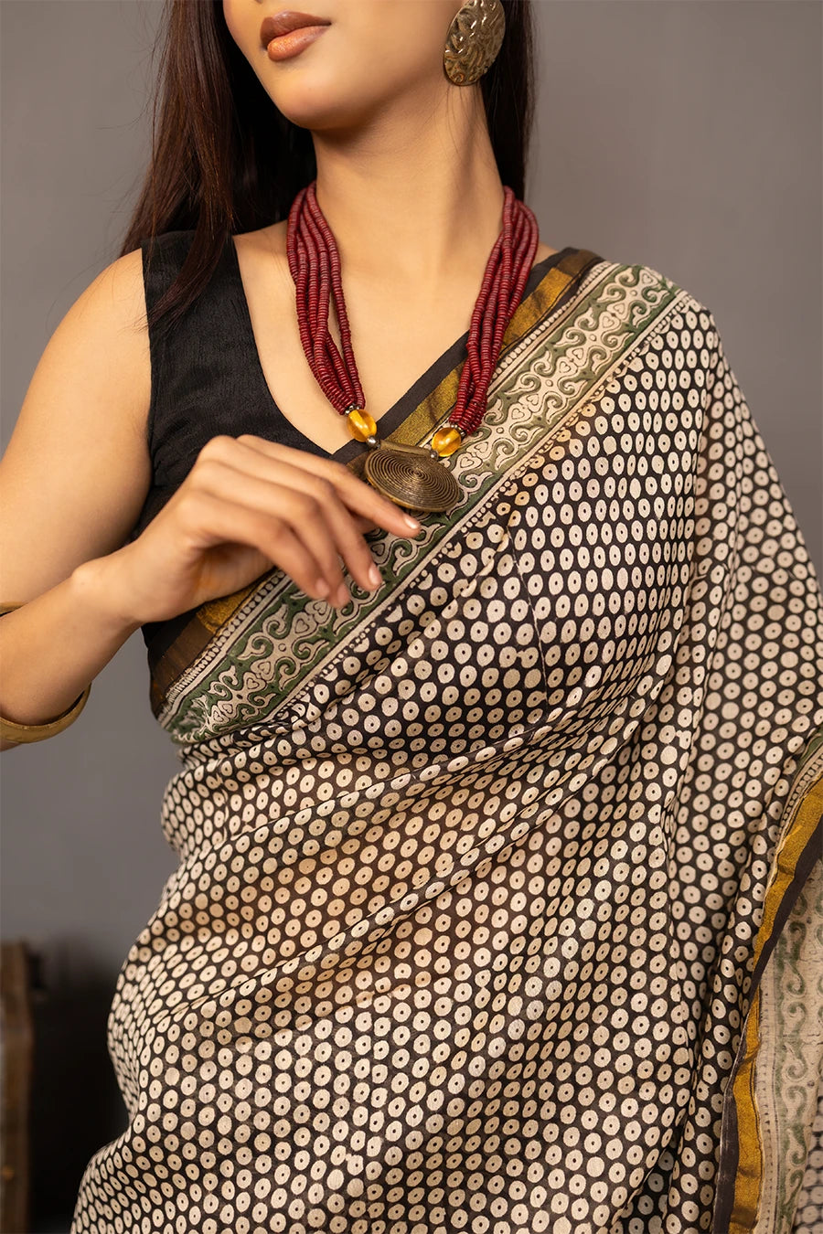 Woman wearing a patterned saree with a grey background