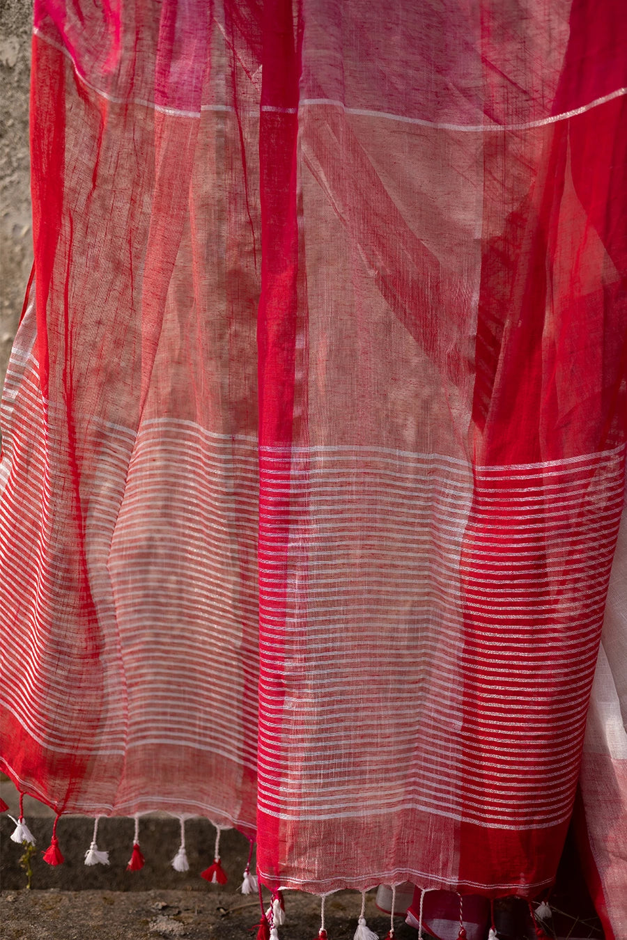 Woman wearing a red and white check red saree against a textured wall