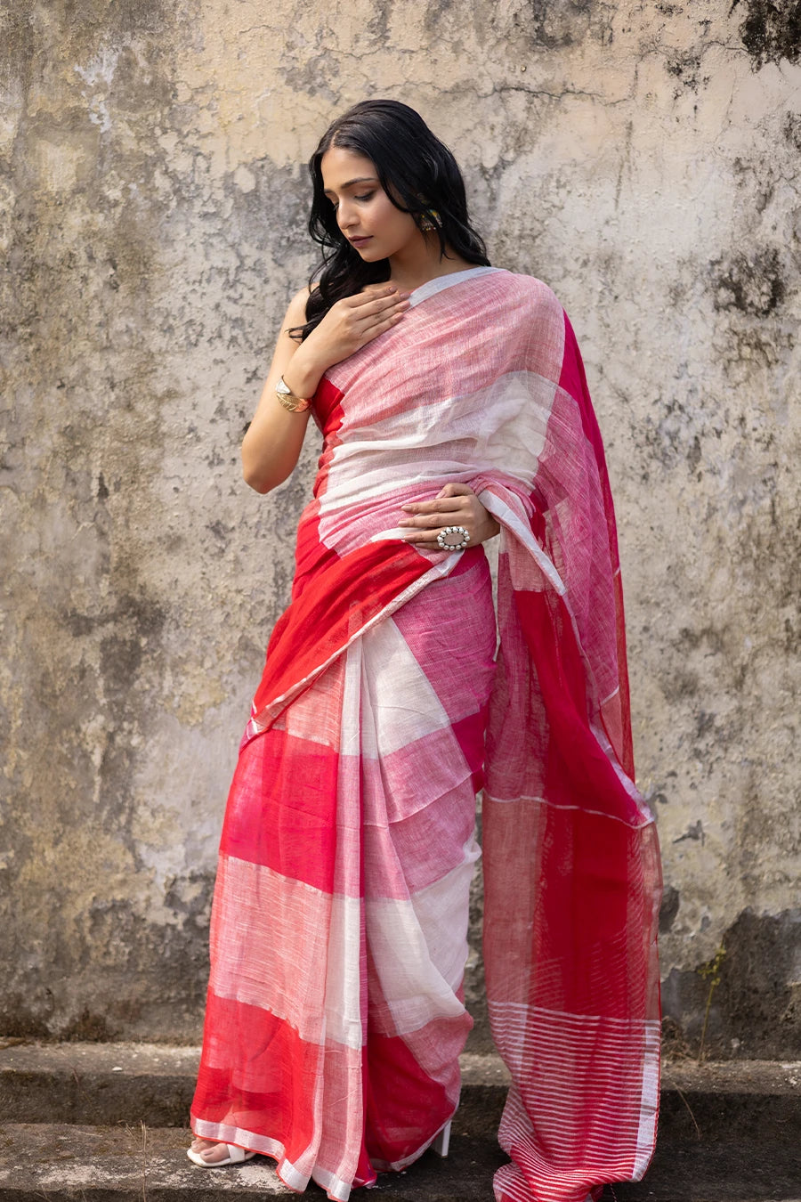 Woman wearing a red and white check red saree against a textured wall