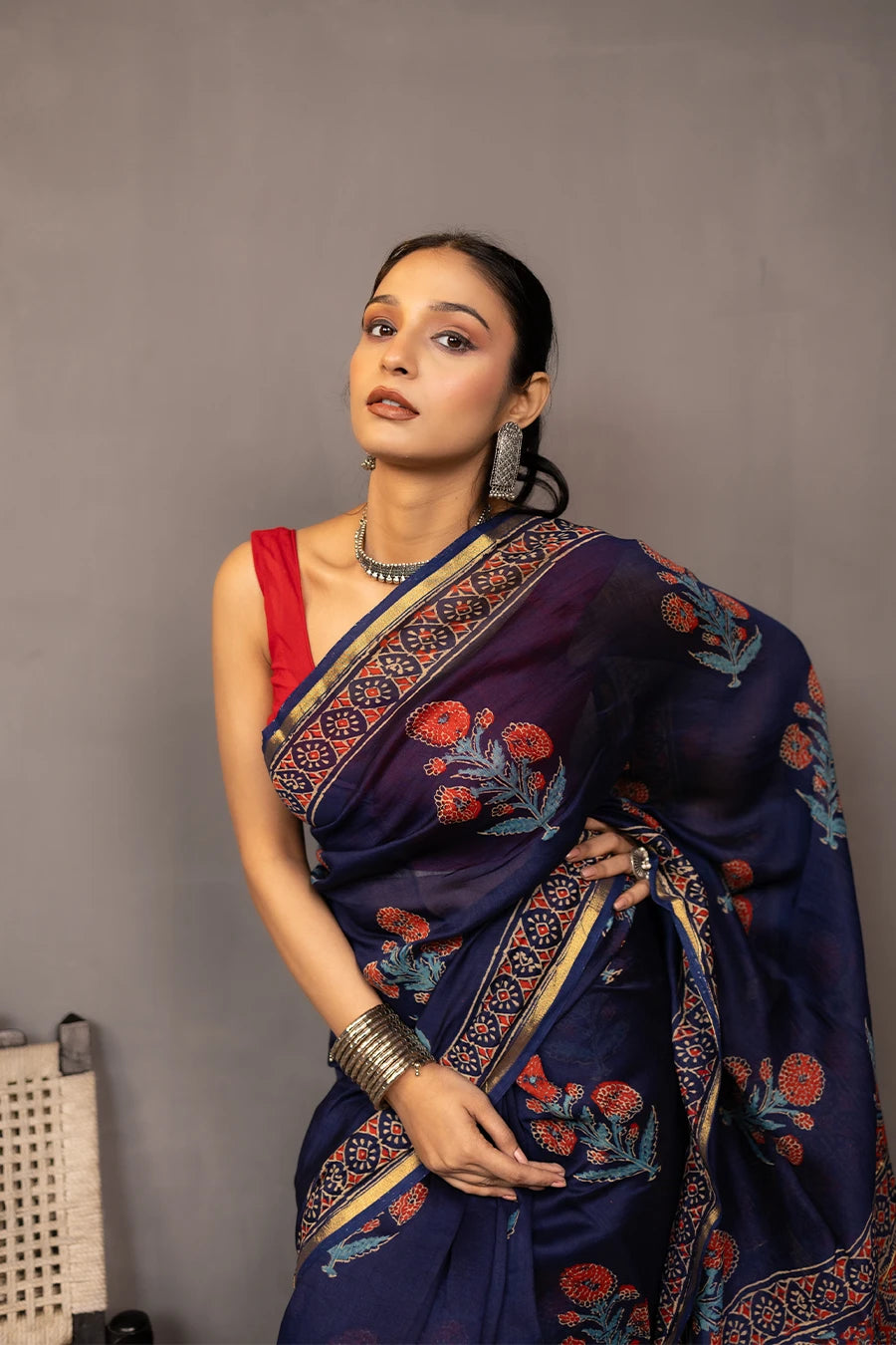 Woman wearing a blue saree with a red blouse against a grey background