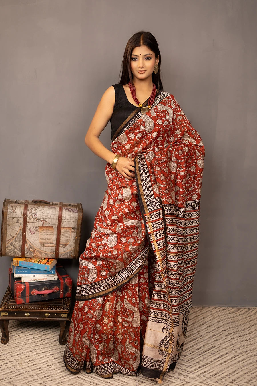 Woman wearing a red and black saree with a patterned background