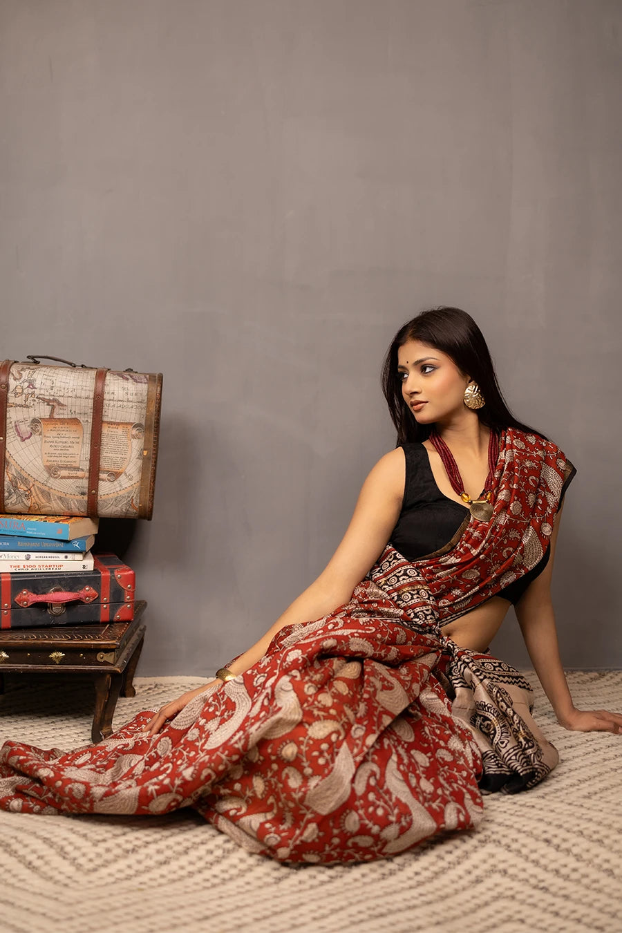 Woman wearing a red and black saree with a patterned background