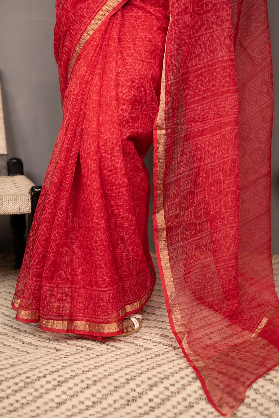 Woman wearing a red saree with a white blouse against a grey background