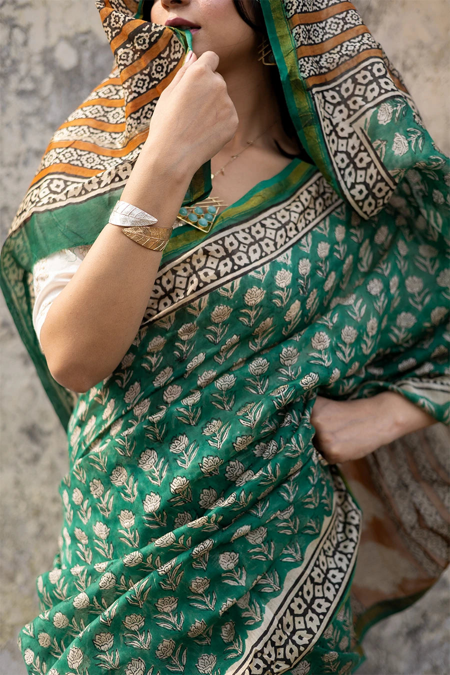 Woman in a green saree with a textured wall background