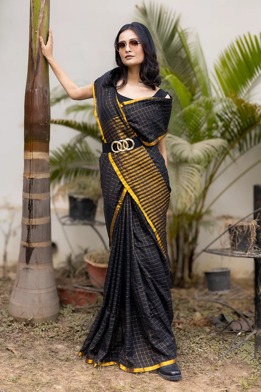 Model wearing a black and gold designer saree with a modern draped style suitable for festive and party wear.