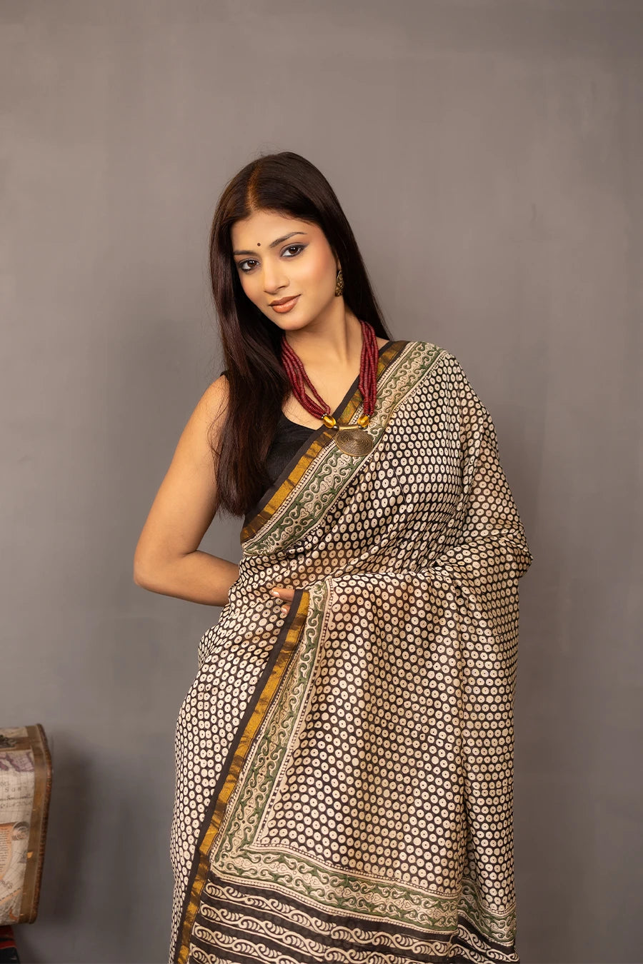 Woman wearing a patterned saree with a grey background