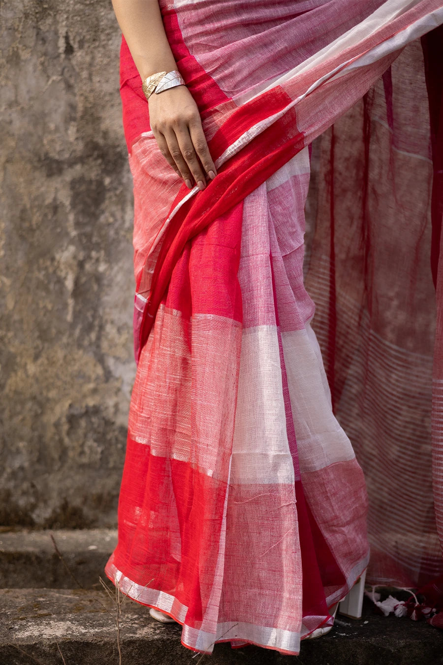 Woman wearing a red and white check red saree against a textured wall