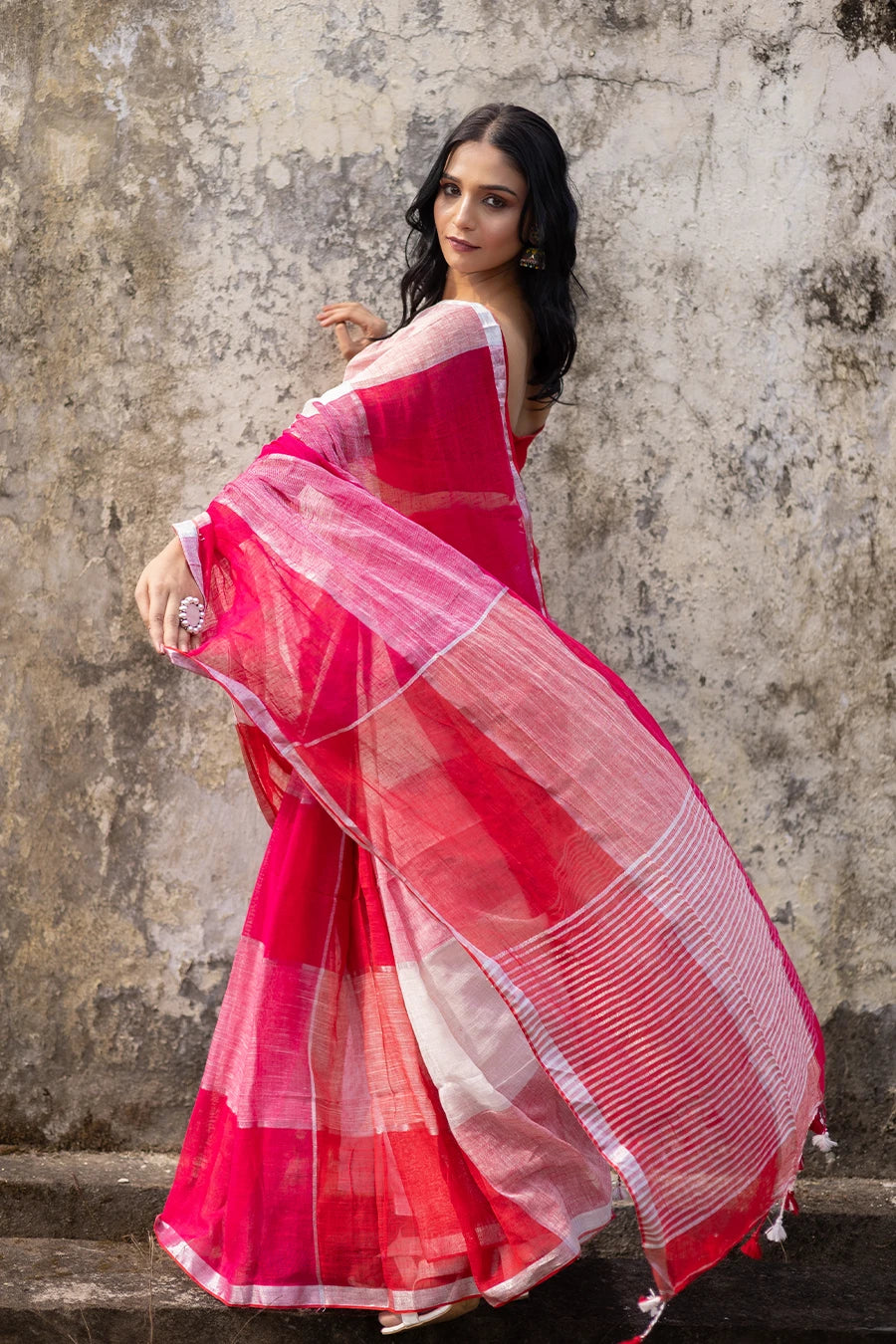Woman wearing a red and white check red saree against a textured wall