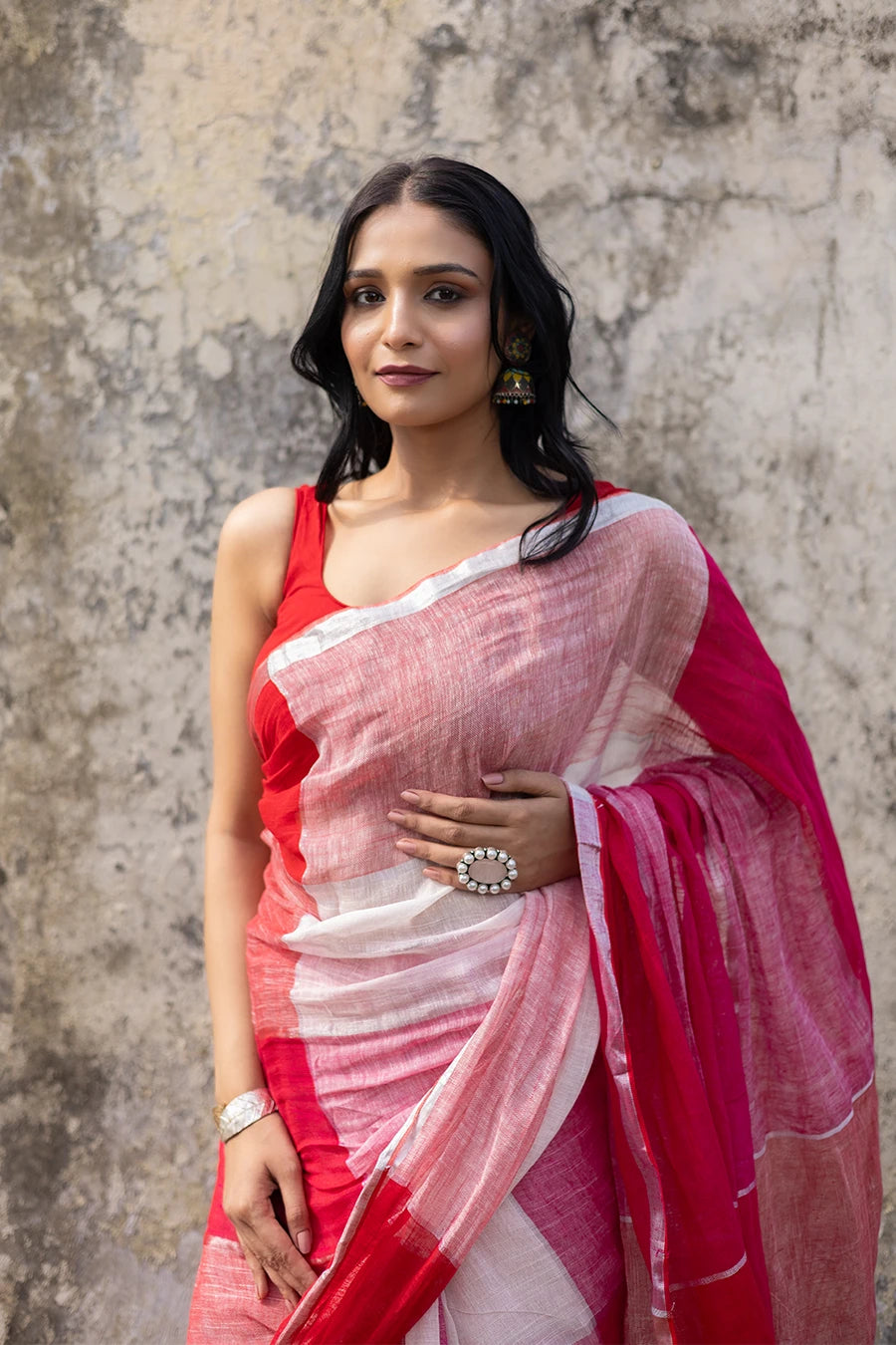 Woman wearing a red and white check red saree against a textured wall