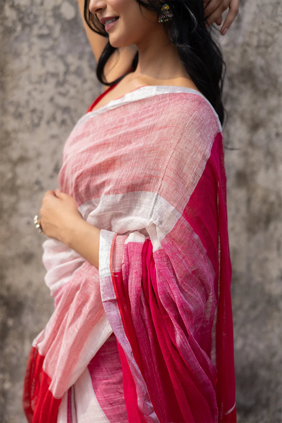 Woman wearing a red and white check red saree against a textured wall
