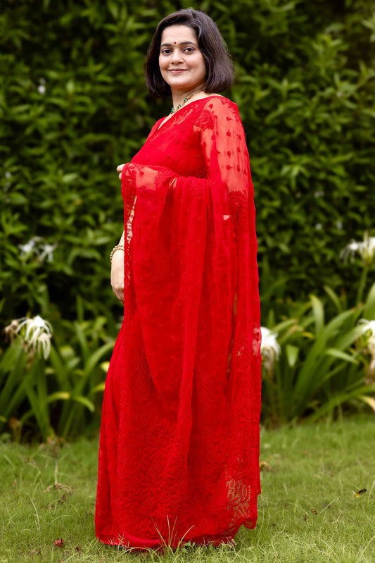 Woman wearing red georgette Lucknowi chikankari saree with blouse, side pose