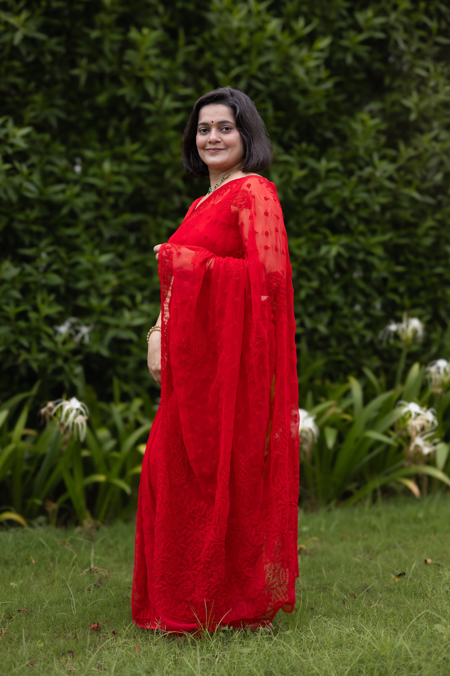 Woman wearing red georgette Lucknowi chikankari saree with blouse, side pose
