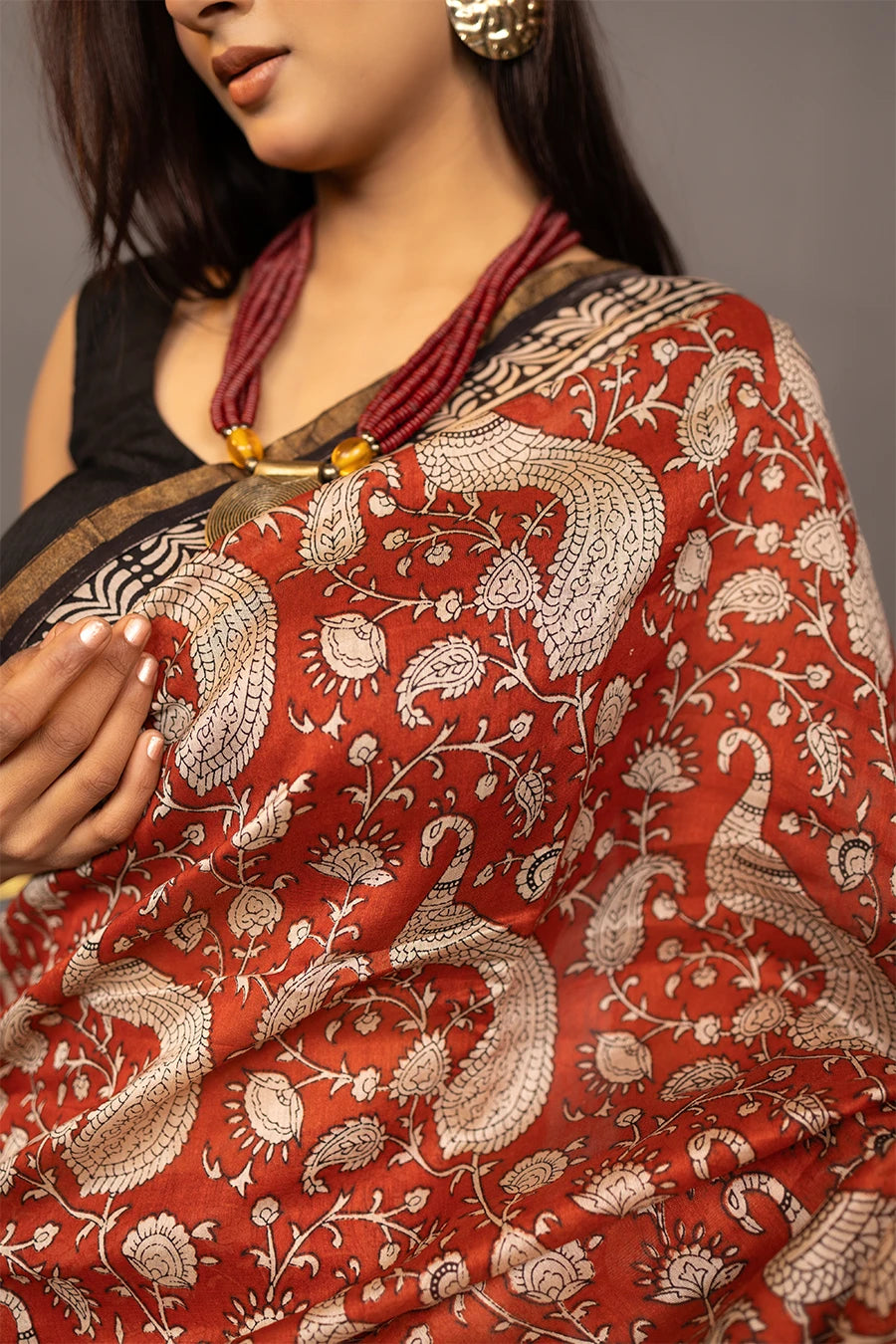 Woman wearing a red and black saree with a patterned background