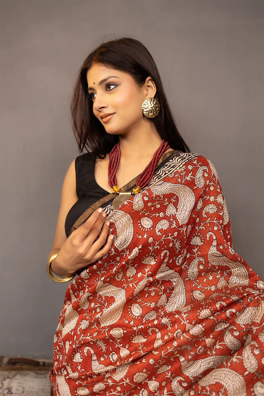 Woman wearing a red and black saree with a patterned background
