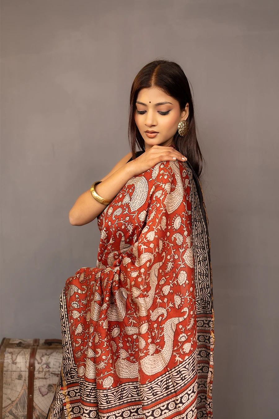 Woman wearing a red and black saree with a patterned background