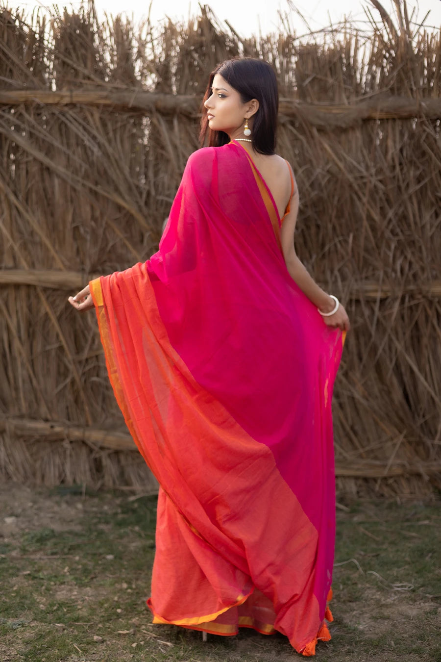 Model wearing a magenta and orange mul cotton saree with contrast border and tassel detailing, suitable for daily wear, casual outings, and festive occasions.