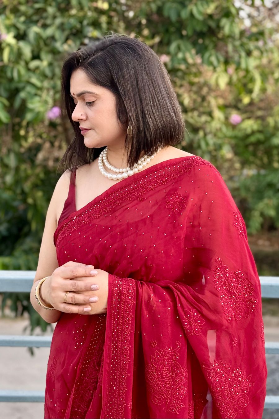 Model in red organza chikankari saree with mukaish work, elegant front drape view.