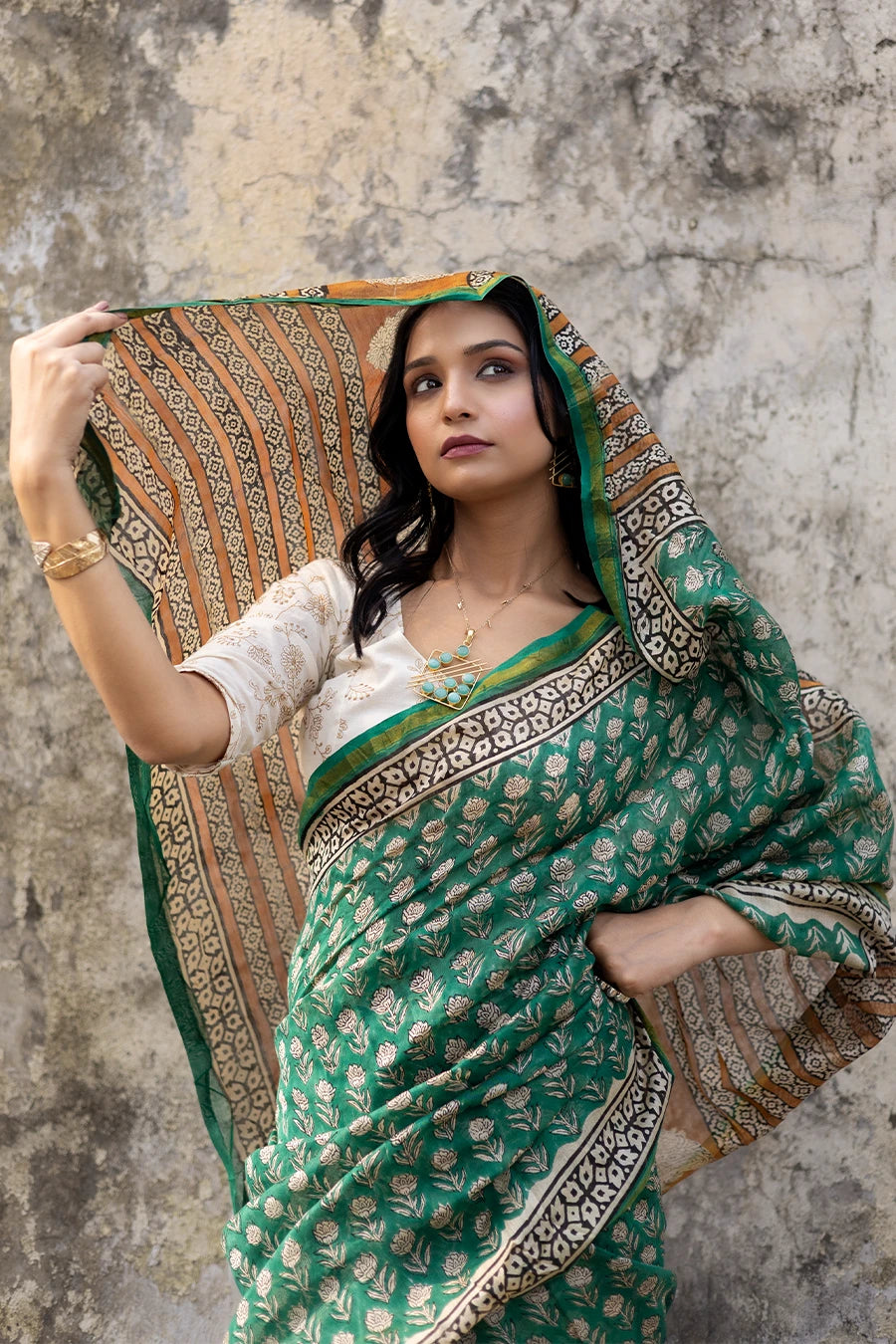 Woman in a green saree with a textured wall background
