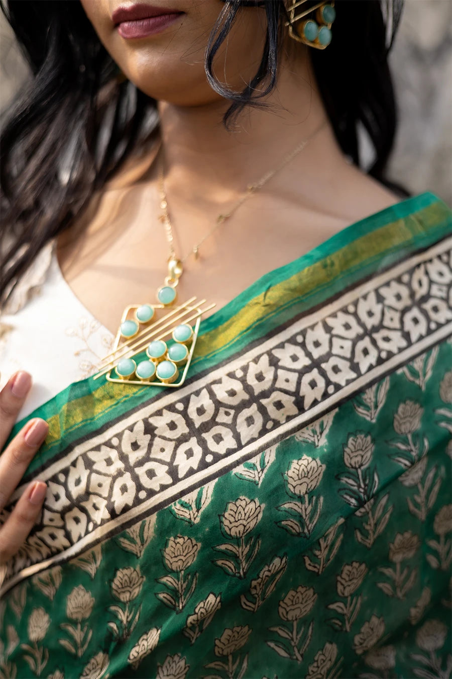 Woman in a green saree with a textured wall background