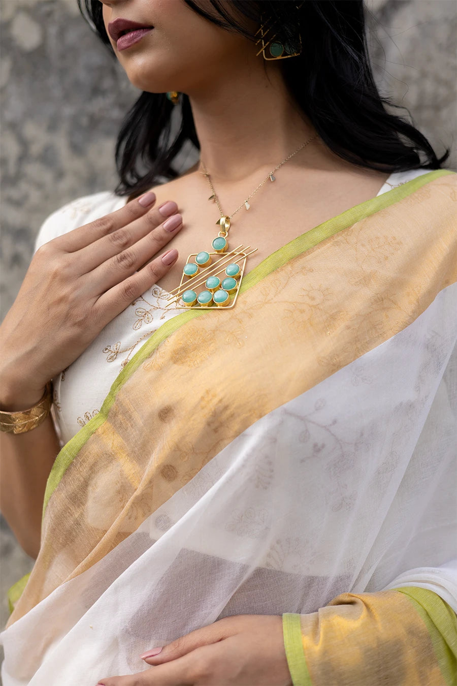 Woman wearing a white and yellow saree against a textured wall